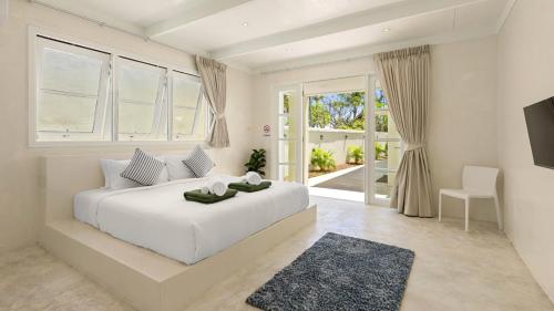 a white bedroom with a large white bed and windows at Aqua Vista 02 - 4BR Villa Near the Beach in Amphoe Koh Samui