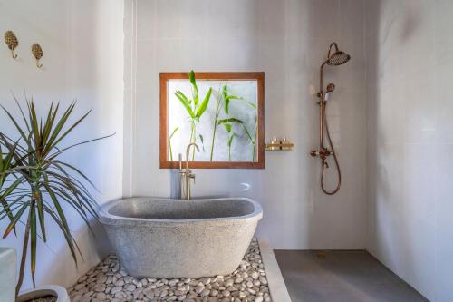 a bath tub in a bathroom with a plant at Luxury 3BR Noa Villa Private Pool in Gili Air