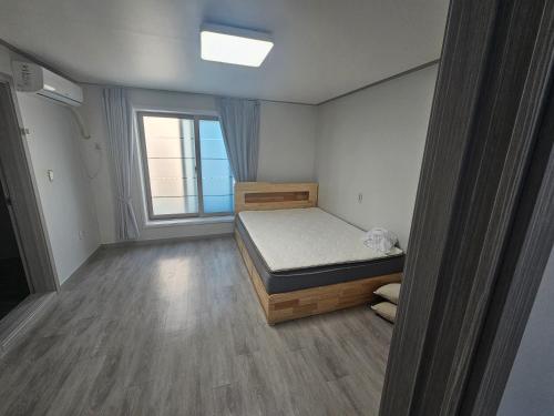 a small bedroom with a bed and a window at 인천공항 인근 여행자 숙소 in Incheon