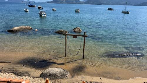 a beach with a swing in the water with boats at EXCLUSIVIDADE à beira-mar in Angra dos Reis