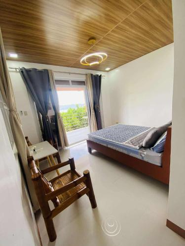 a bedroom with a bed and a chair and a window at CJ's Place Mabini in Mabini