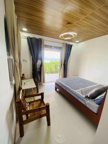 a bedroom with a bed and a desk and a window at CJ's Place Mabini in Mabini