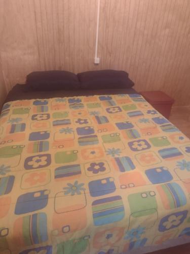a bed with a colorful comforter on top of it at Cabaña Bellavista in Cochamó