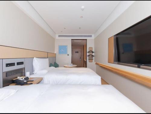 a hotel room with two beds and a flat screen tv at JI Hotel Beijing Qianmen Street Zhushikou in Beijing