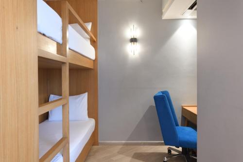 a bedroom with a bunk bed and a desk and a blue chair at Ramada Encore by Wyndham Rajbagh Srinagar in Srinagar