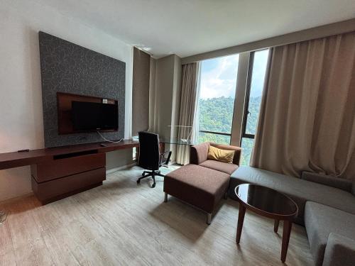 a living room with a couch and a desk with a television at QQ Empire Damansara hotel room in Petaling Jaya