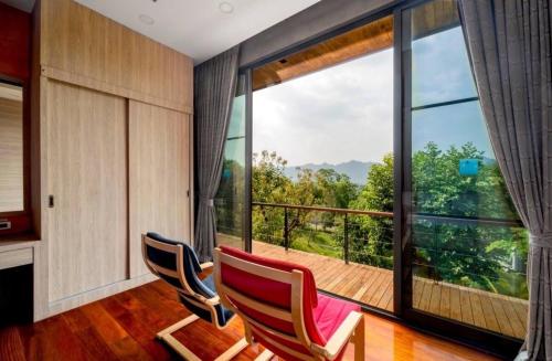 a room with two chairs and a large window at The Height Khaoyai Resort in Ban Huai Sok Noi