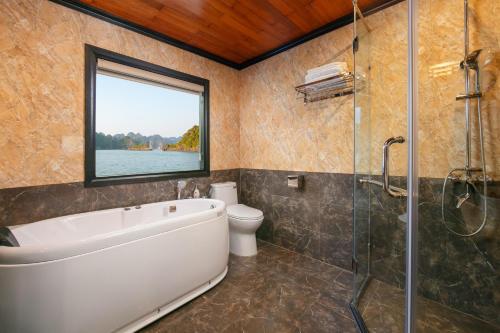 a bathroom with a tub and a toilet and a window at Halong Arcadia Cruise in Ha Long