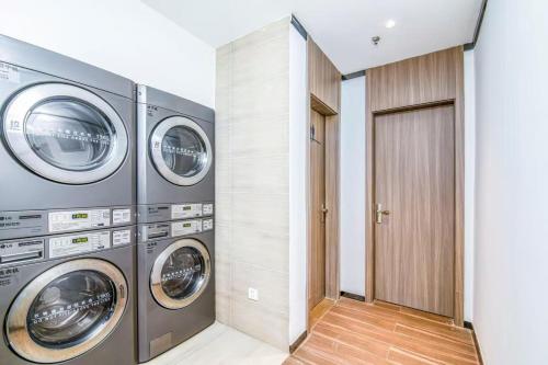 a laundry room with three washing machines and a door at Hanting Hotel Beijing Daxing Caiyu in Beijing