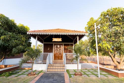 a house with a wooden door and some trees at Mango Resort Washi Hills in Kolhapur