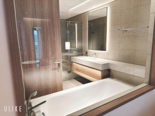 a bathroom with a tub and a sink and a mirror at Venus Sea View By Alacarte in Ha Long