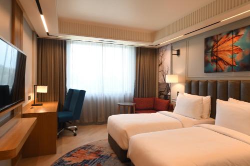 a hotel room with two beds and a flat screen tv at Ramada Encore by Wyndham Rajbagh Srinagar in Srinagar