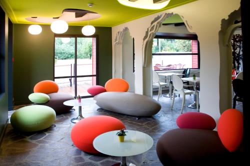 a room with colorful chairs and tables and windows at Logis Auberge De La Foret in Le Gâvre