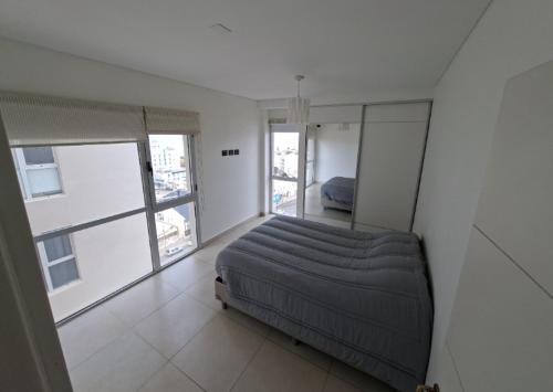 a bedroom with a bed in a room with windows at Espacio Chacabuco in Comodoro Rivadavia