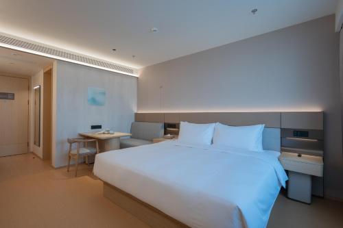 ein Schlafzimmer mit einem großen weißen Bett und einem Schreibtisch in der Unterkunft 全季北京亦庄荣华南路酒店 in Peking
