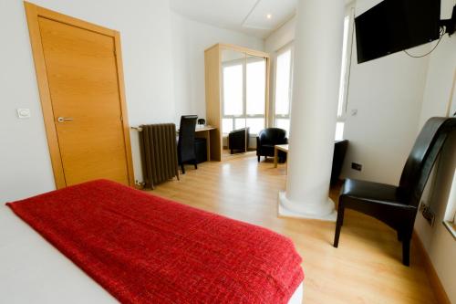 a bedroom with a red rug and a room with a desk at Pension Kursaal in Donostia-San Sebastián