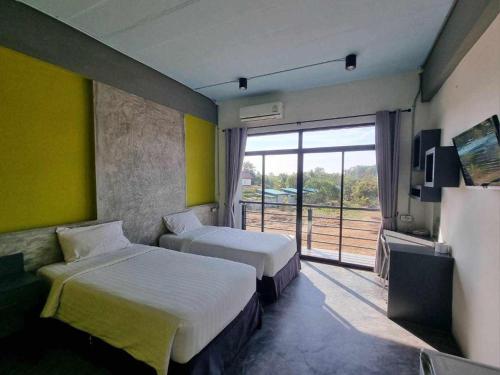a hotel room with two beds and a window at Pornsiri Hotel Sisaket in Si Sa Ket