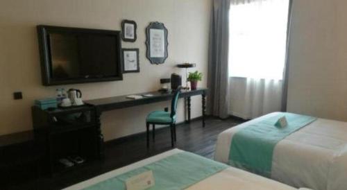 a hotel room with a desk with a television and a bed at Xana Hotelle·Tianshui Shangyi Plaza in Tianshui
