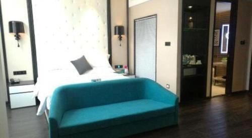 a bedroom with a blue couch in front of a bed at Xana Hotelle·Tianshui Shangyi Plaza in Tianshui