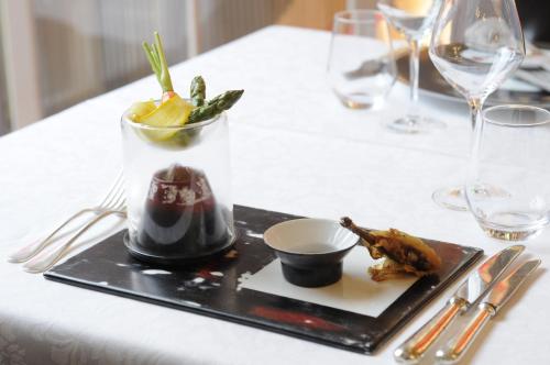 a black plate with food on a white table at Demeures & Châteaux La Belle Meuniere in Royat