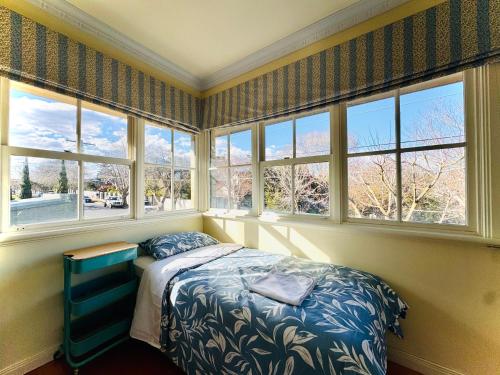 Cozy Beachside 5BR Home with Pool & Rumpus & King beds في ملبورن: غرفة نوم بنوافذ وسرير فيها