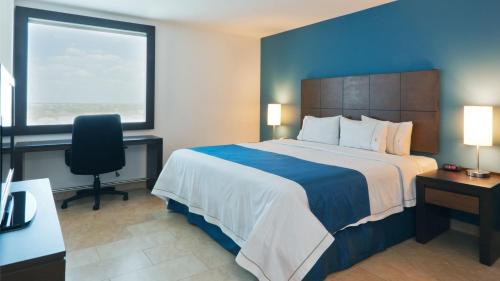 a hotel room with a bed and a desk and a window at Holiday Inn Express Mérida by IHG in Mérida