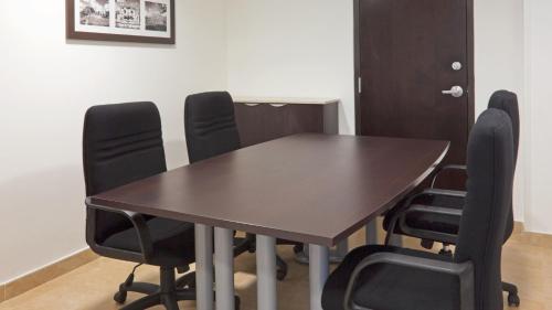 a conference room with a wooden table and black chairs at Holiday Inn Express Mérida by IHG in Mérida