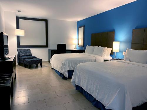a hotel room with two beds and a chair at Holiday Inn Express Mérida by IHG in Mérida
