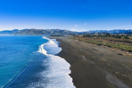 an aerial view of a black beach with the ocean at Mountain View - Kaikoura Holiday Home in Kaikoura