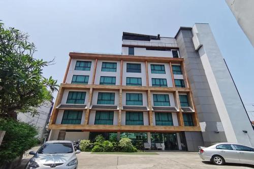 a building with cars parked in front of it at Holatel Hotel Phitsanulok in Phitsanulok