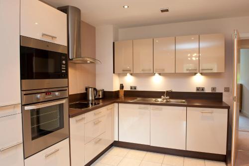 a kitchen with white cabinets and stainless steel appliances at The Sands Sea Front Apartments in Scarborough