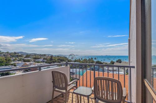 a balcony with two chairs and a view of the ocean at OCEAN VIEWS 10 in Airlie Beach