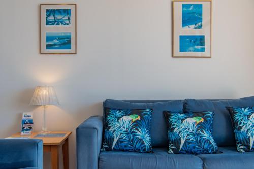 a blue couch with two tropical pillows on it at OCEAN VIEWS 10 in Airlie Beach