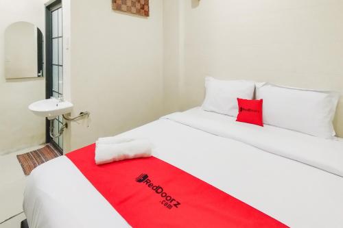 a white bed with a red blanket on it at RedDoorz at Rejoss Lux Medan in Medan