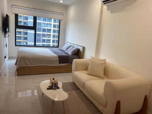 a living room with a couch and a bed at Honey Vinhomes in Long Bình