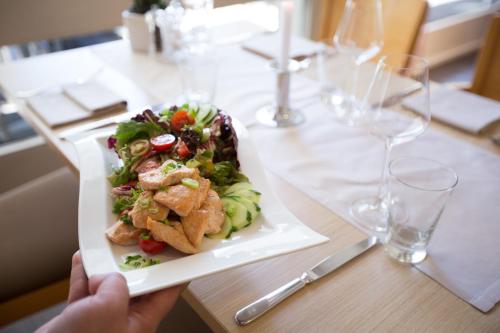 a person holding a plate of food on a table at Garner Hotel Augsburg Nord by IHG in Augsburg