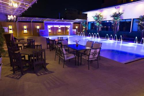 a restaurant with tables and chairs next to a swimming pool at Ruean Phae Royal Park Hotel in Phitsanulok