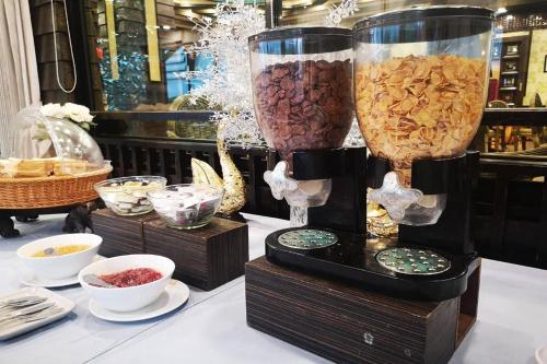 a table with two vases filled with different types of food at Ruean Phae Royal Park Hotel in Phitsanulok