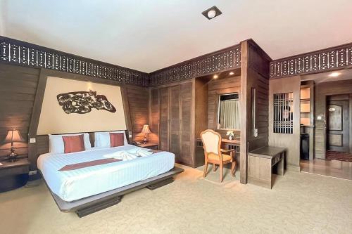 a bedroom with a bed and a desk and a table at Ruean Phae Royal Park Hotel in Phitsanulok