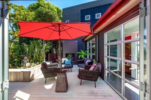 a patio with chairs and a red umbrella at Top Floor Bed and Breakfast in Paraparaumu Beach