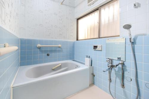 ein blaues Bad mit einer Badewanne und einer Dusche in der Unterkunft Kasai Cozy House in Tokio