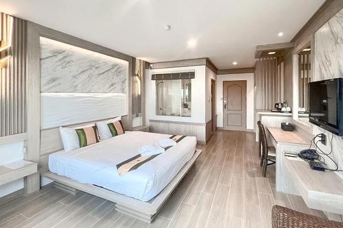 a bedroom with a bed and a desk and a television at Ruean Phae Royal Park Hotel in Phitsanulok