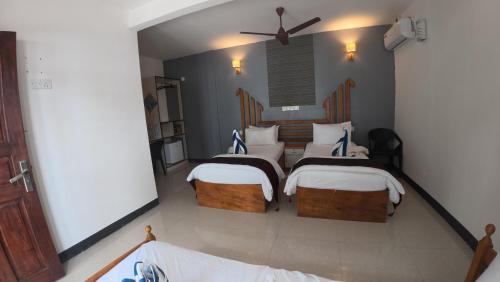 a bedroom with two beds with white pillows at Liberty Guesthouse Maldives in Mahibadhoo