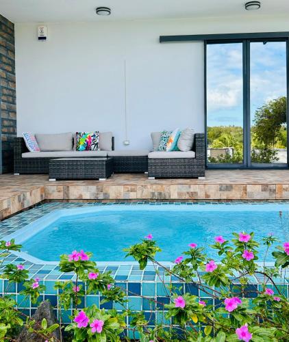 a swimming pool with flowers in front of a house at Lakeview Bellemare Villa in Belle Mare