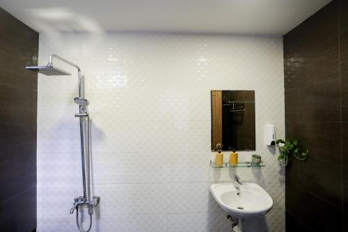 a white tiled bathroom with a sink and a mirror at Xanh Homestay in Da Nang