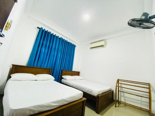 a bedroom with two beds and a blue curtain at TK Homes in Badulla
