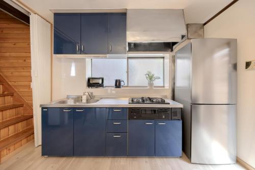 eine Küche mit blauen Schränken und einem Kühlschrank aus Edelstahl in der Unterkunft Kasai Cozy House in Tokio