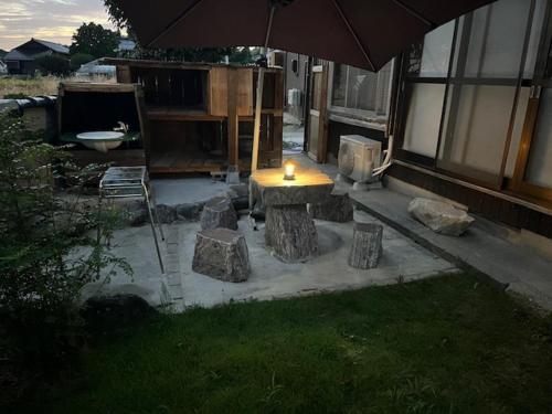 a patio with an umbrella and a table and rocks at 大切なペットと一緒に泊まれる一棟貸し in Sado