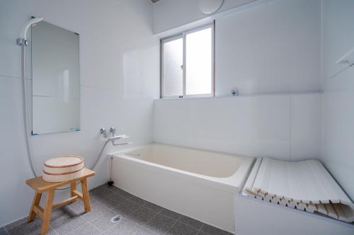 baño blanco con bañera y taburete en 大切なペットと一緒に泊まれる一棟貸し, en Sado