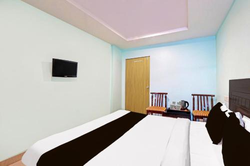 a bedroom with a bed and a tv and two chairs at Collection O Kurnool Formerly Sai Priyanka Inn in Kurnool